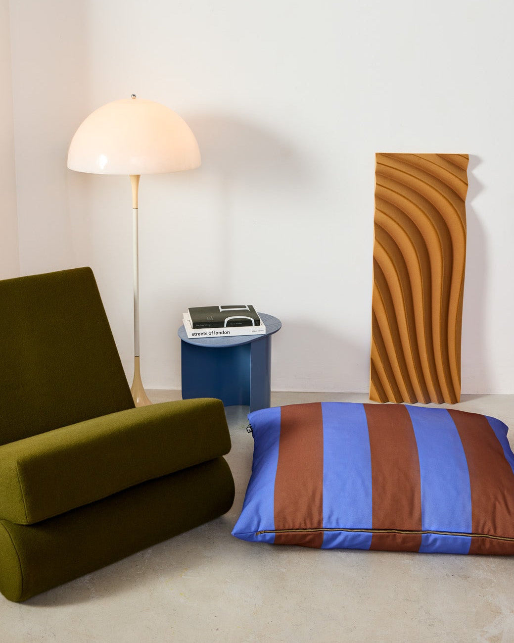 Modern interior with a green chair, striped dog pillow, and abstract wall art.