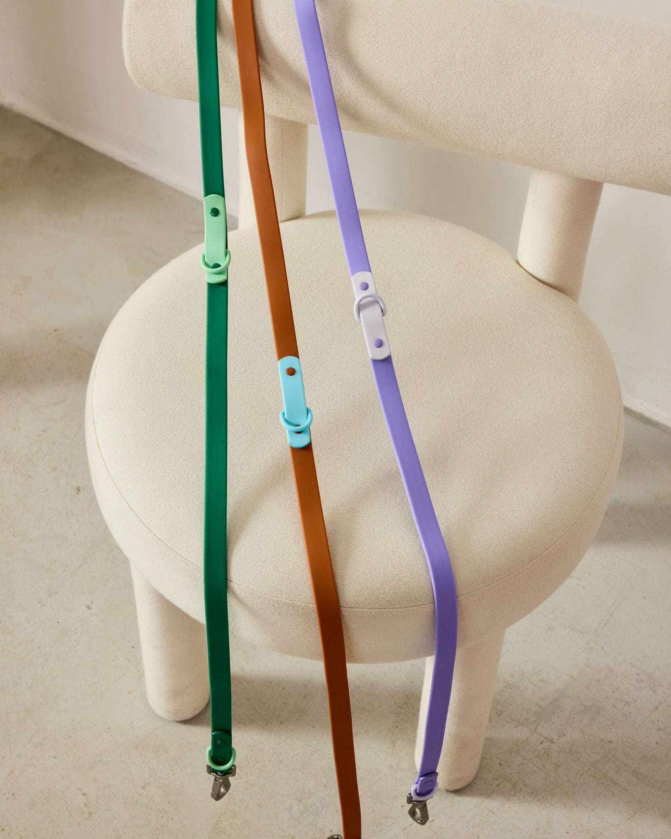 Three colorful dog leashes on a white chair.