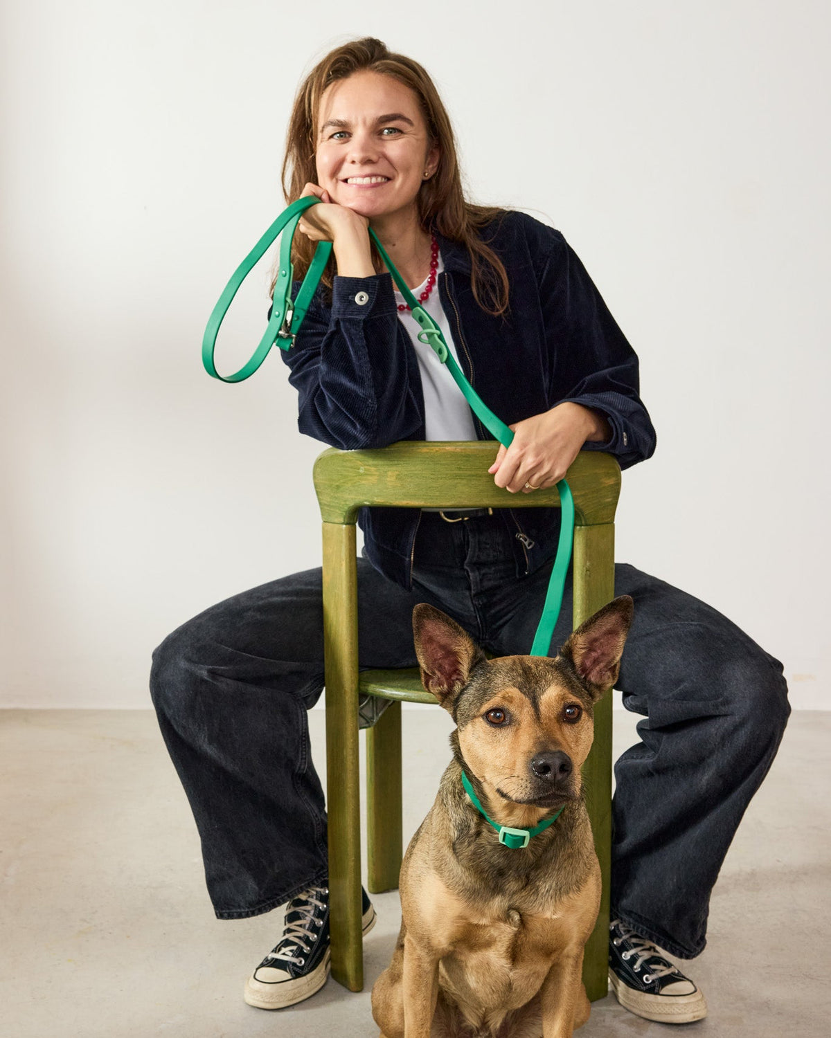 Smiling woman on a chair with her dog wearing a Fritz collar and leash